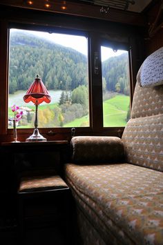 a couch sitting in front of a window with a lamp on it's side