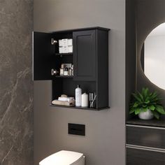 a white toilet sitting next to a black cabinet in a bathroom under a round mirror