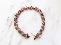 "This is a beautiful sterling silver 925 & 18K rose gold filled ladies tennis bracelet. It features large purple glass stones & pave set cubic zirconia stones. All stones are present & secure. The box clasp has two safety latches on each side. The clasp is signed DL China 925/18K GP. The bracelet is 7 7/8\" long x 1/4\" wide. Total weight is 10.7dwt/16.6grams. This is a vintage, previously owned bracelet. Therefore, light wear can be expected. There is no visible damage." Rose Gold Tennis Bracelet With Pave Setting As Gift, Elegant Purple Cubic Zirconia Bracelets, Elegant Purple Tennis Bracelet, Elegant Purple Tennis Bracelet For Gift, Ladies Tennis, Bracelet Tennis, Box Clasp, Womens Tennis, Tennis Bracelet Diamond