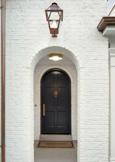 an instagramted photo of a black front door and light fixture on a white brick building