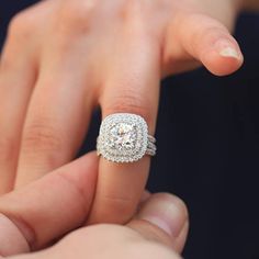 a close up of a person's hand holding an engagement ring