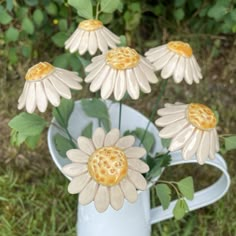 four ceramic flowers in a watering can