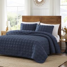 a bed in a bedroom with blue comforter and pillows