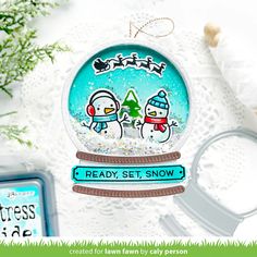 a snow globe ornament with two penguins on it and the words ready set snow