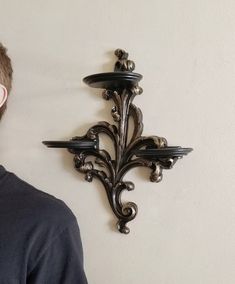 a man standing in front of a wall mounted clock on the side of a wall