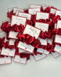 there are many red ribbons on the table with place cards in them for guests to sign