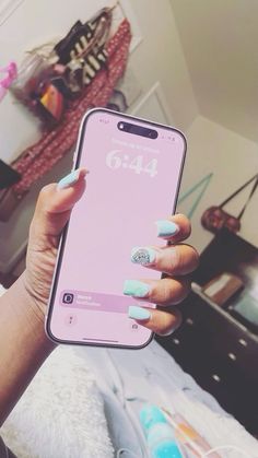 a woman's hand holding an iphone with blue and pink nails