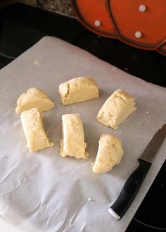 four pieces of bread sitting on top of a piece of paper next to a knife