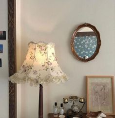 a lamp sitting on top of a wooden table next to a mirror and pictures above it