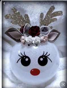 a white ornament with a red nose and flower in it's hair