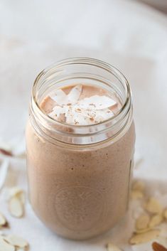 a glass jar filled with food sitting on top of a white table covered in nuts