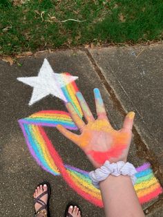 a child's hand painted with rainbow and stars on the ground next to a sidewalk