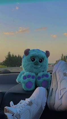 a stuffed animal sitting on top of a car seat next to a pair of sneakers