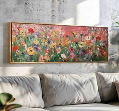 a painting hanging on the wall above a couch in front of a potted plant