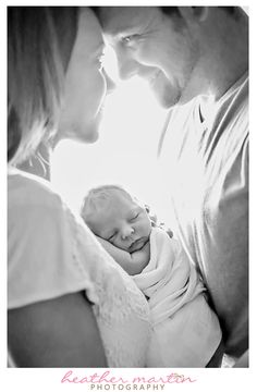 a man and woman holding a baby in their arms