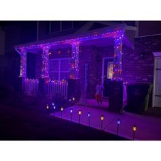 a house with christmas lights on the front and side of it in purple hues