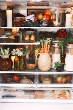 an open refrigerator filled with lots of food and drinks on it's shelves next to candles