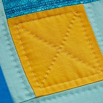 a close up view of the corner of a blue and yellow piece of fabric with stitching on it