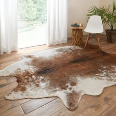 a brown and white area rug in a living room with wood flooring next to a window