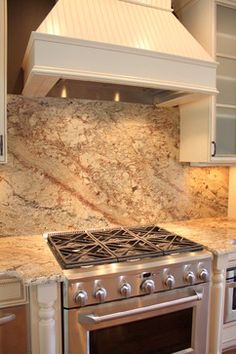 a stove top oven sitting inside of a kitchen next to white cabinets and counter tops