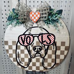 a wooden sign with a dog's head wearing sunglasses and a bow on it