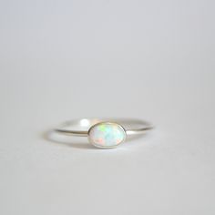 "Dainty opal ring with small 6x4mm oval lab grown opal. The stone is set by hand into an oval bezel. The band is thin at 1mm. Polished for a beautiful shine finish. *OPAL COLOR OPTIONS- **Important: Please let me know your choice of opal color in the \"Note to Seller\" box at checkout. -White opal -Blue opal -Seagreen opal -Lavender opal *MATERIAL OPTIONS- -14k Gold Filled -Sterling Silver -14k Solid (Yellow) Gold -14k Solid White Gold Made to order in your size. Sizes in drop down box are U.S. Dainty Opal Ring, Oval Opal Ring, Opal Gold Ring, Japanese Study, Delicate Silver Rings, Gold Opal Ring, Estate Jewelry Rings, Family Ring, Gold Bar Earrings