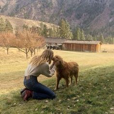 a woman kneeling down next to a brown dog on top of a grass covered field