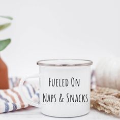 a white enamel mug that says fueled on naps and snacks