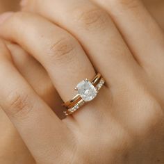 a woman's hand with a diamond ring on top of her finger and the other hand holding an engagement ring