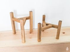 two wooden stools sitting next to each other on top of a wood floor in front of a white wall