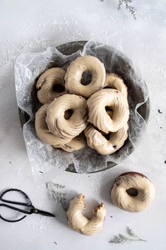 some doughnuts are sitting in a bowl on a table with scissors and other items