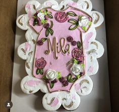 a decorated cake in the shape of a shield with roses and leaves on it's side