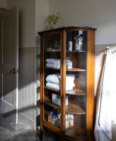 a wooden cabinet with towels and other items in it