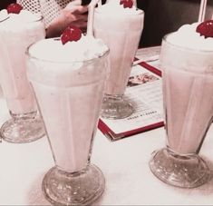 three glasses filled with milkshakes sitting on top of a table