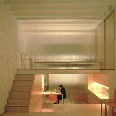 a person sitting at a table in a room with stairs leading up to the ceiling