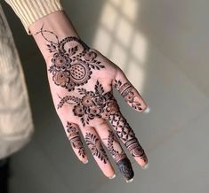 a woman's hand with henna tattoos on it