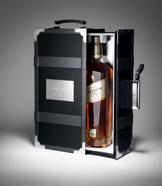 a bottle of whisky in a black box on a gray background with the lid open