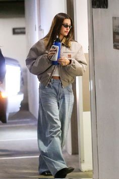 a woman is walking down the street with her cell phone