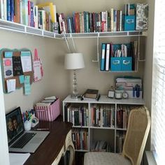 a desk with a laptop and bookshelf full of books