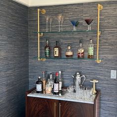 a bar with wine glasses and liquor bottles on the shelf above it is decorated with gold pipes