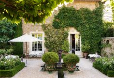 an outdoor dining area with potted plants and umbrellas in front of a house