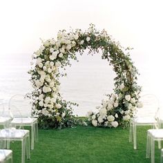 an outdoor ceremony setup with white flowers and clear chairs