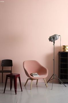 two chairs and a lamp in front of a pink wall