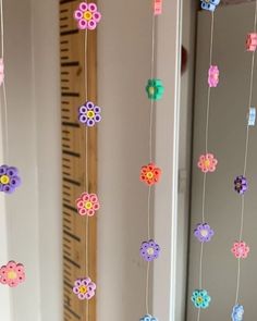 colorful paper flowers hanging from strings in front of a mirror and wall with other items on it