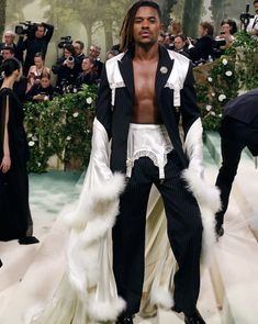 a man with dreadlocks standing in front of a group of people at a fashion show