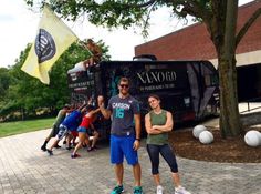 two people standing in front of a tour bus with one person holding up a flag