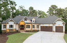 a large white house with two garages and trees in the background