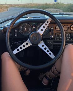 a woman sitting in the driver's seat of a car with her feet on the steering wheel