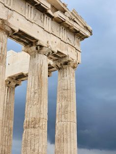 an ancient building with three columns under a cloudy sky