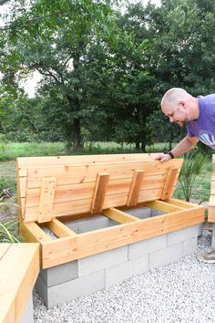 a man is placing plants in a planter box on the side of a bench